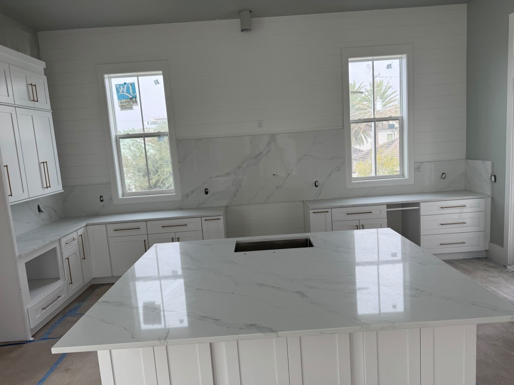 Bright coastal kitchen with a calacatta quartz island and full-height slab backsplash
