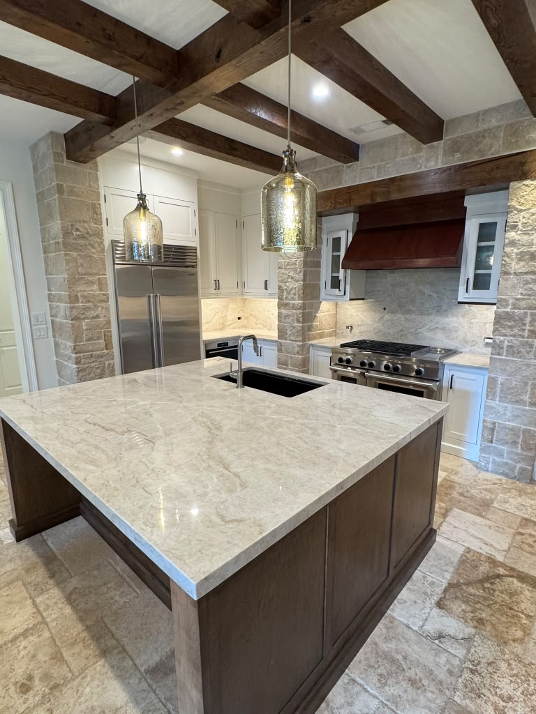 Taj Mahal quartzite island in a stone-and-beam luxury kitchen